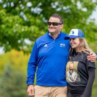 Two players smile and hug while watching a game